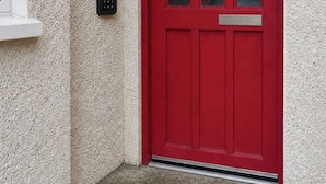 A red door with a keypad lock and a small mailbox on the wall. - Lovely Clydebank Apartment - 2 Bedrooms (Clydebank)