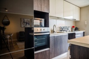 A modern kitchen with a built-in oven, a microwave, and a stainless steel sink. - Luxury 2 Bedroom Apartment with Pool and Parking (Las Condes)