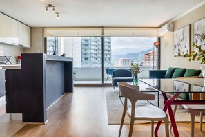 Eine moderne Wohnung mit Küche, Essbereich und einem Balkon mit Blick auf die Stadt.