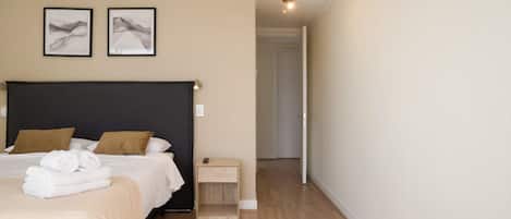 A bedroom with a large bed, a bedside table, and two framed pictures on the wall.