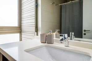 A bathroom with a white sink, two soap dispensers, a mirror, and a shower curtain. - Luxury 2 Bedroom Apartment with Pool and Parking (Las Condes)