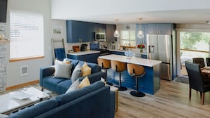 Una cocina moderna con armarios azules, una isla central con taburetes y un comedor con mesa y sillas.