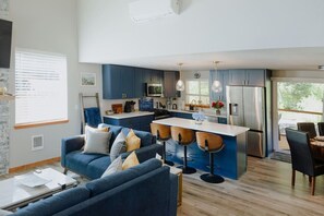 Una cocina moderna con armarios azules, una isla central con taburetes y un comedor con mesa y sillas.
