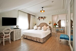 Une chambre d’hôtel avec un grand lit, un bureau, une chaise, une coiffeuse et un miroir.
