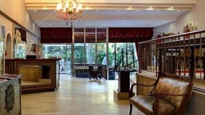 Un vestíbulo espacioso con un mostrador de recepción de madera, una araña y vistas al exterior.