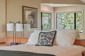 A hotel room with a bed, a nightstand, a lamp, and a window with a view of greenery. - River Ridge at Mt Bachelor River Oohs Mountain Ahs (Bend)