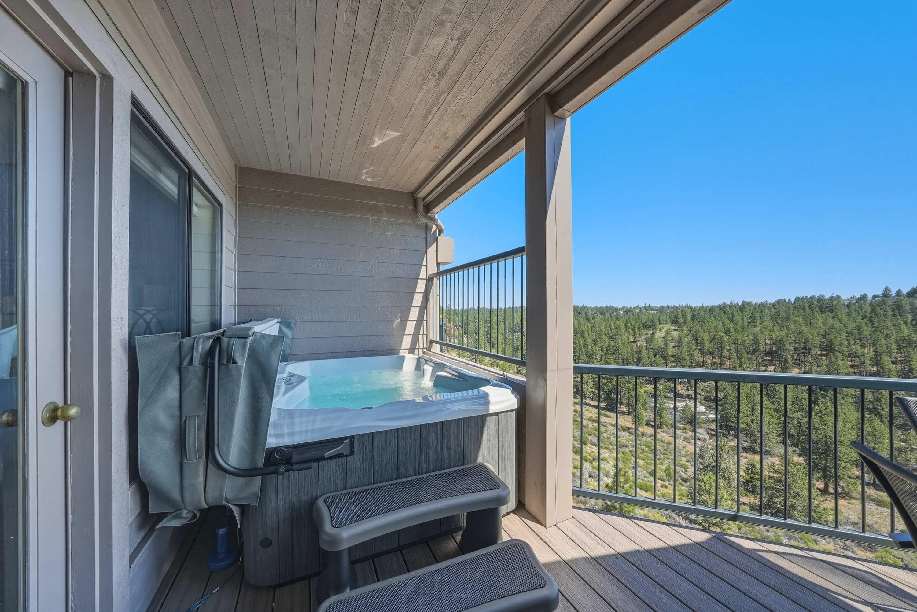 A hot tub on a wooden deck with a view of a forest.