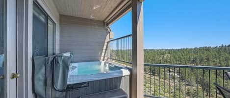 A hot tub on a wooden deck with a view of a forest.
