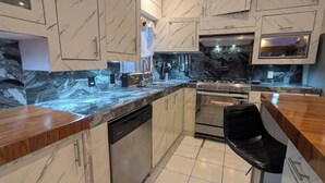 Una cocina moderna con encimeras de mármol, electrodomésticos de acero inoxidable y horno empotrado.