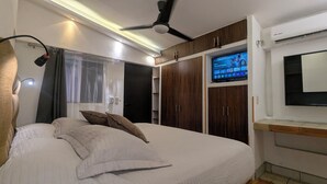 Un dormitorio con cama, ventilador de techo, televisor y armarios empotrados.
