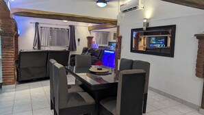 Un comedor con mesa de vidrio, sillas negras y televisor montado en la pared.