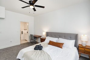 Ein Schlafzimmer mit Bett, Schreibtisch, Stuhl, Nachttisch und Deckenventilator.