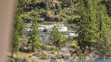 Paisagem natural com rio, árvores e terreno rochoso.