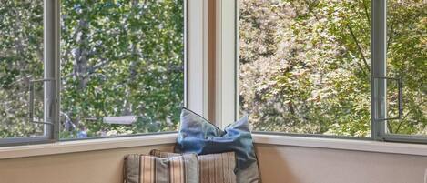 A window seat with a view of trees and a bench.