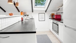Et moderne køkken med ovenlys, hvide skabe og en sort bordplade.