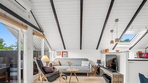 Et moderne interiør med sofa, stole, et fjernsyn og et grillområde.