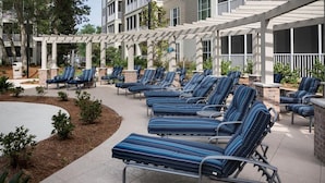 Een overdekt terras met meerdere lounge stoelen en een pergola.
