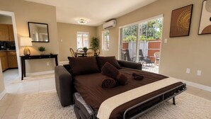 Een slaapkamer met een bed, een bank, een eettafel en een keukenhoek.