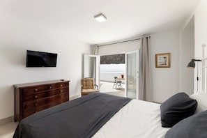 A bedroom with a bed, dresser, TV, chair, and balcony view. - Home2Book Elegant Villa with Jacuzzi Costa Teguise (Teguise)