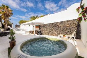 A hot tub with a stone wall and a white building with a patio area. - Home2Book Elegant Villa with Jacuzzi Costa Teguise (Teguise)