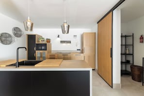 A modern kitchen with a central island, pendant lighting, and built-in appliances. - Home2Book Elegant Villa with Jacuzzi Costa Teguise (Teguise)