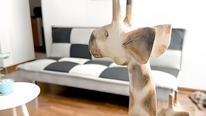 Una escultura de jirafa en una sala de estar con un sofá y una mesita.