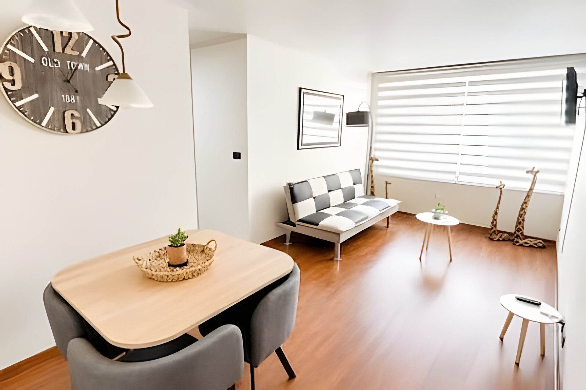 A modern living space with a wooden dining table, a sofa, a small side table, and a giraffe decoration.
