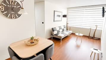 A modern living space with a wooden dining table, a sofa, a small side table, and a giraffe decoration.