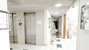 Un pasillo limpio y moderno con piso estampado, una planta en maceta y un ascensor.