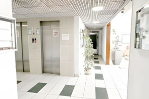 Passadís modern i net amb un paviment estampat, una planta en test i un ascensor.