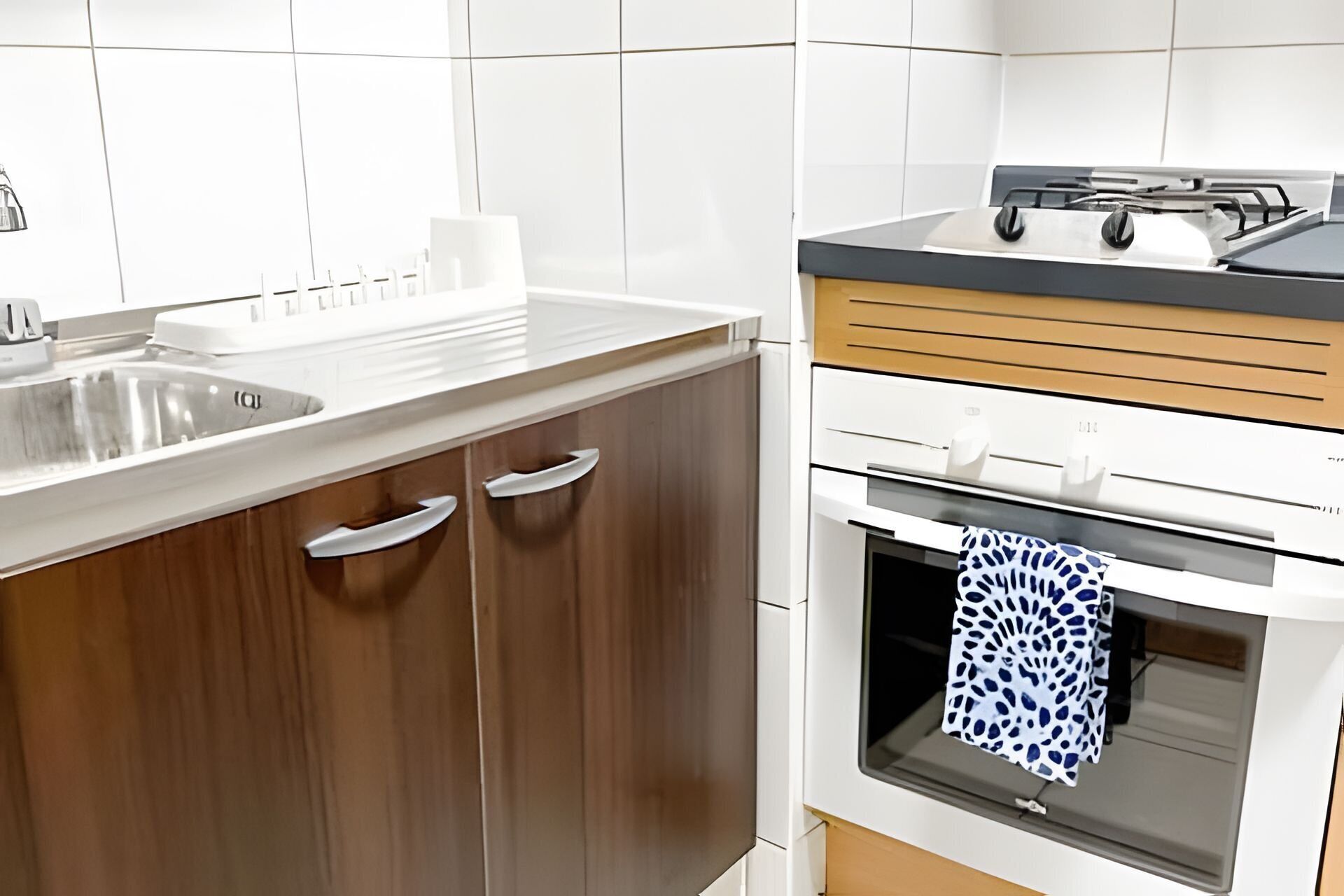 A kitchen with white cabinets, a stainless steel sink, and a stove.