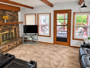 A living room with a fireplace, a television, and a seating area with a sofa and chairs.