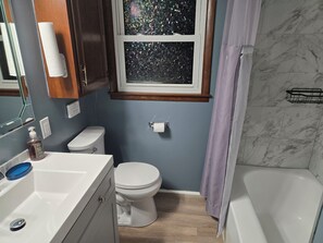 A bathroom with a toilet, sink, and bathtub. - Cozy 3 BDRM Home 3 minutes to Arrowhead & Kauffman Stadium (Kansas City)