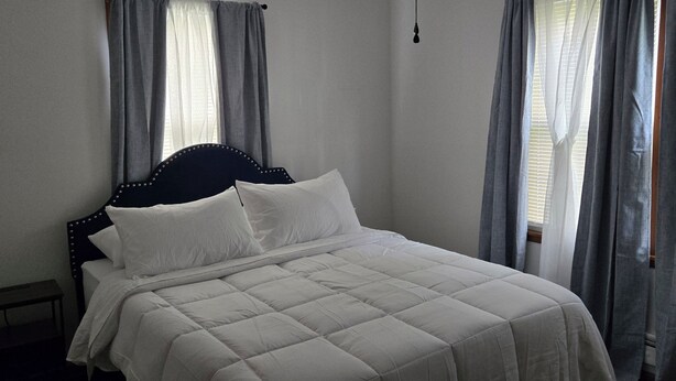 Um quarto com cama, cortinas e luminária pendente.