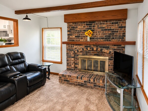 A living room with a brick fireplace, a leather sofa, and a glass coffee table.