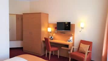 Een hotelkamer met een bed, een bureau, twee stoelen, een televisie en een kledingkast.