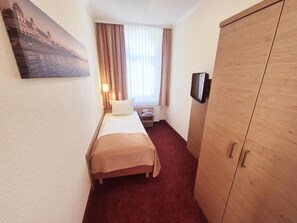 Una habitación de hotel con una cama, televisión, armario y un cuadro en la pared.