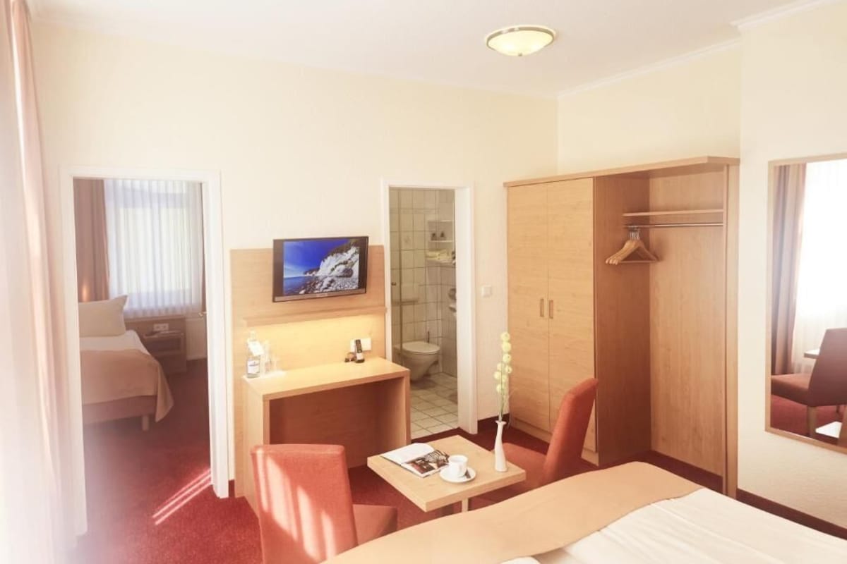 Habitació d'hotel amb llit, escriptori, cadira, televisió, armari i bany.
