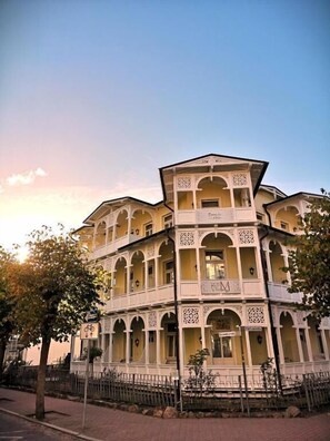 A multi-story building with balconies, arched windows, and a sign indicating a restaurant. - Villa Meeresgruss (Binz)