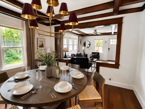 A dining area with a round table set for four, a chandelier, and a view of the outdoors. - Located in the IU Tailgate Fields - Across from Memorial Stadium (Bloomington)