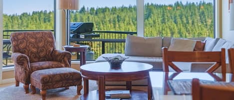 Un balcón con vistas a un bosque, amueblado con un sofá, sillones y una mesa.