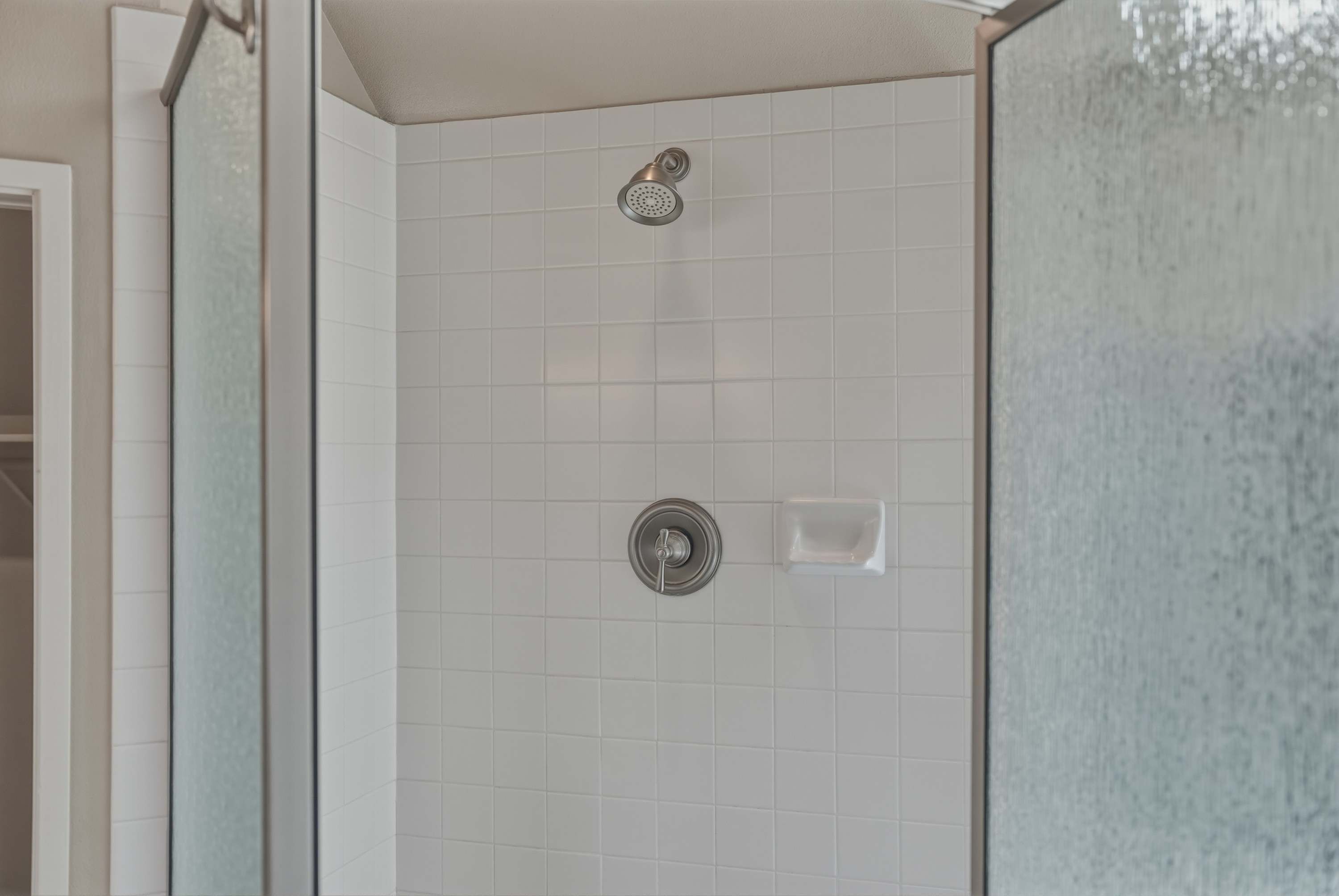 A shower with a handheld showerhead and a wall-mounted control valve.
