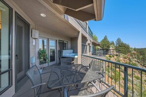 A balcony with a table and chairs, a sliding glass door, and a view of a mountainous landscape. - River Ridge at Mt Bachelor A (Bend)