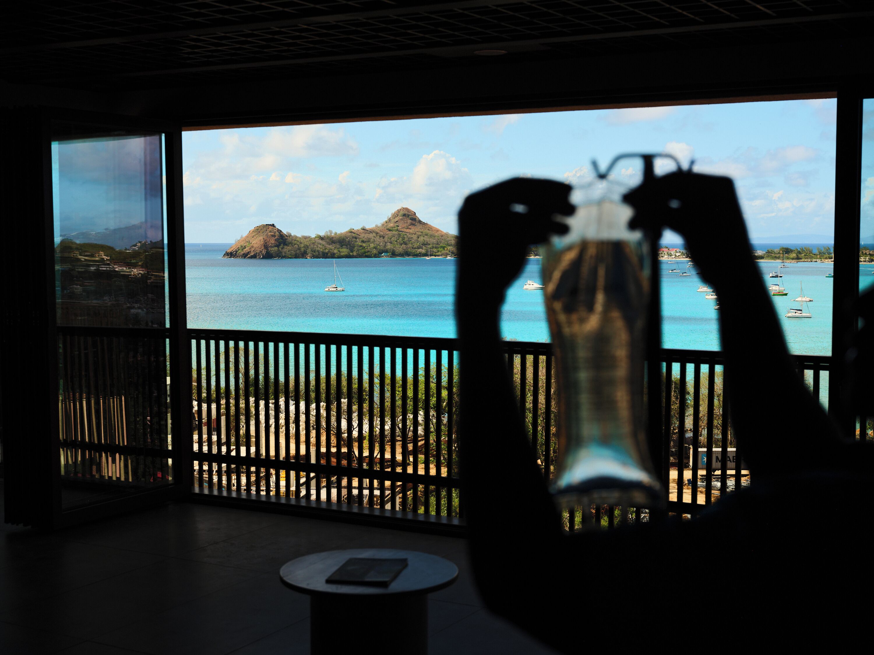Una habitación con un ventanal grande que ofrece vistas al mar con barcos y una pequeña isla.