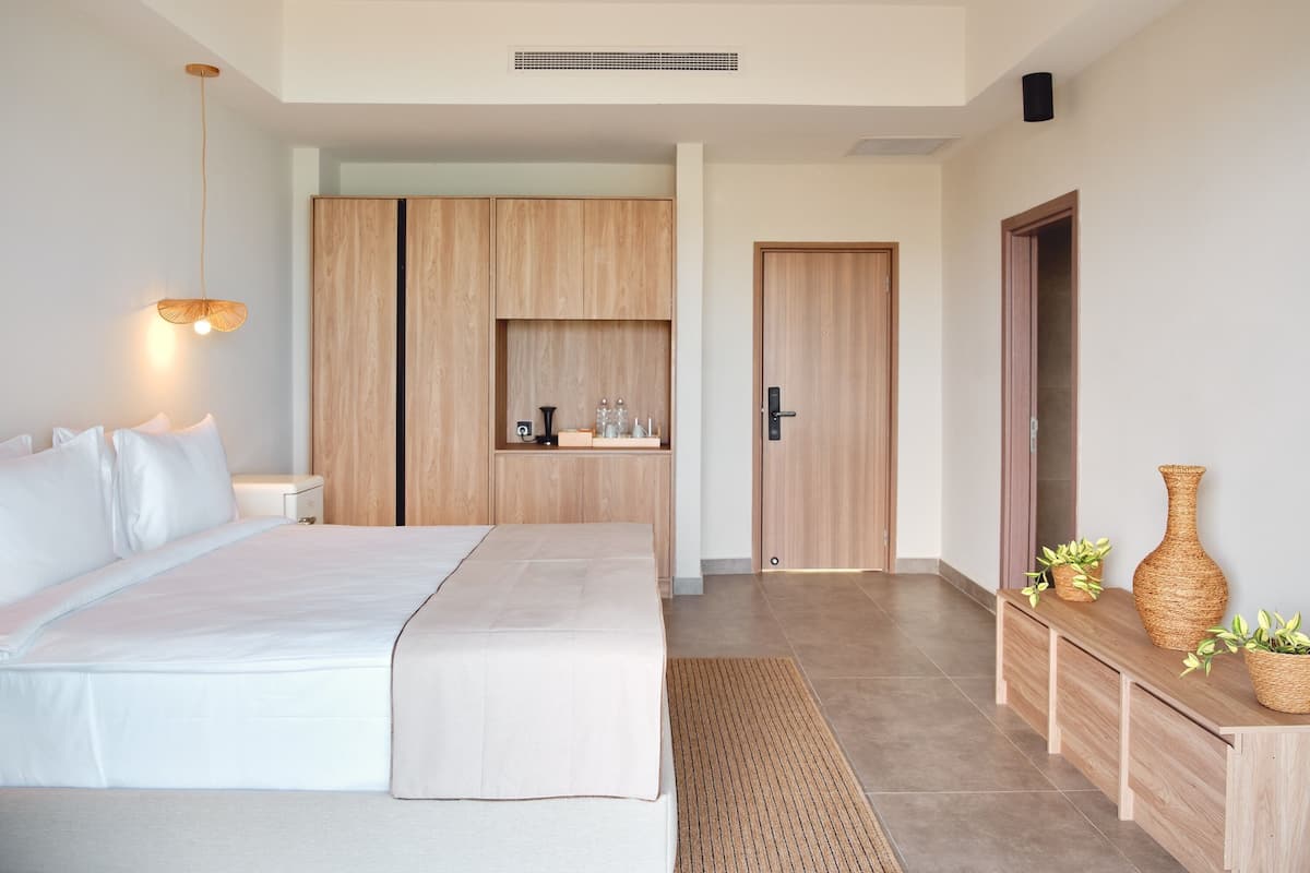 Un dormitorio moderno con una cama grande, armario de madera, mesita de noche y una pequeña estantería con objetos decorativos.