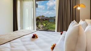 A hotel room with a bed, a view of a garden, and a balcony.