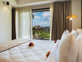 Una habitación de hotel con una cama, vistas a un jardín y un balcón.