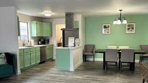 Una cocina moderna con armarios verdes, una isla central y un comedor con mesa y sillas.