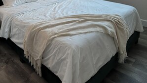 Un dormitorio con cama, luz empotrada en la pared, ventana con vistas y un adorno en la pared.