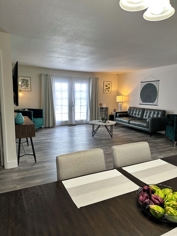 A modern living room with a sofa, dining table, and chairs.
